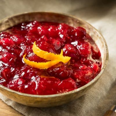 Homemade cranberry orange sauce in wooden bowl garnished with orange zest