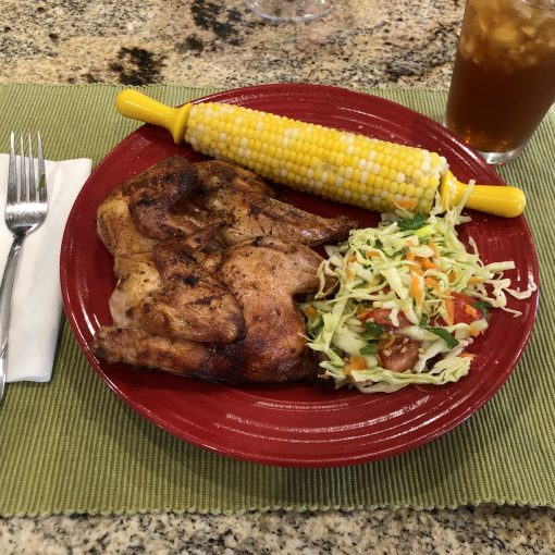 Grilled Spatchcock Cornish Game hen seasoned with Smokin' Barbie barbecue seasoning and served with corn on the cob and slaw.