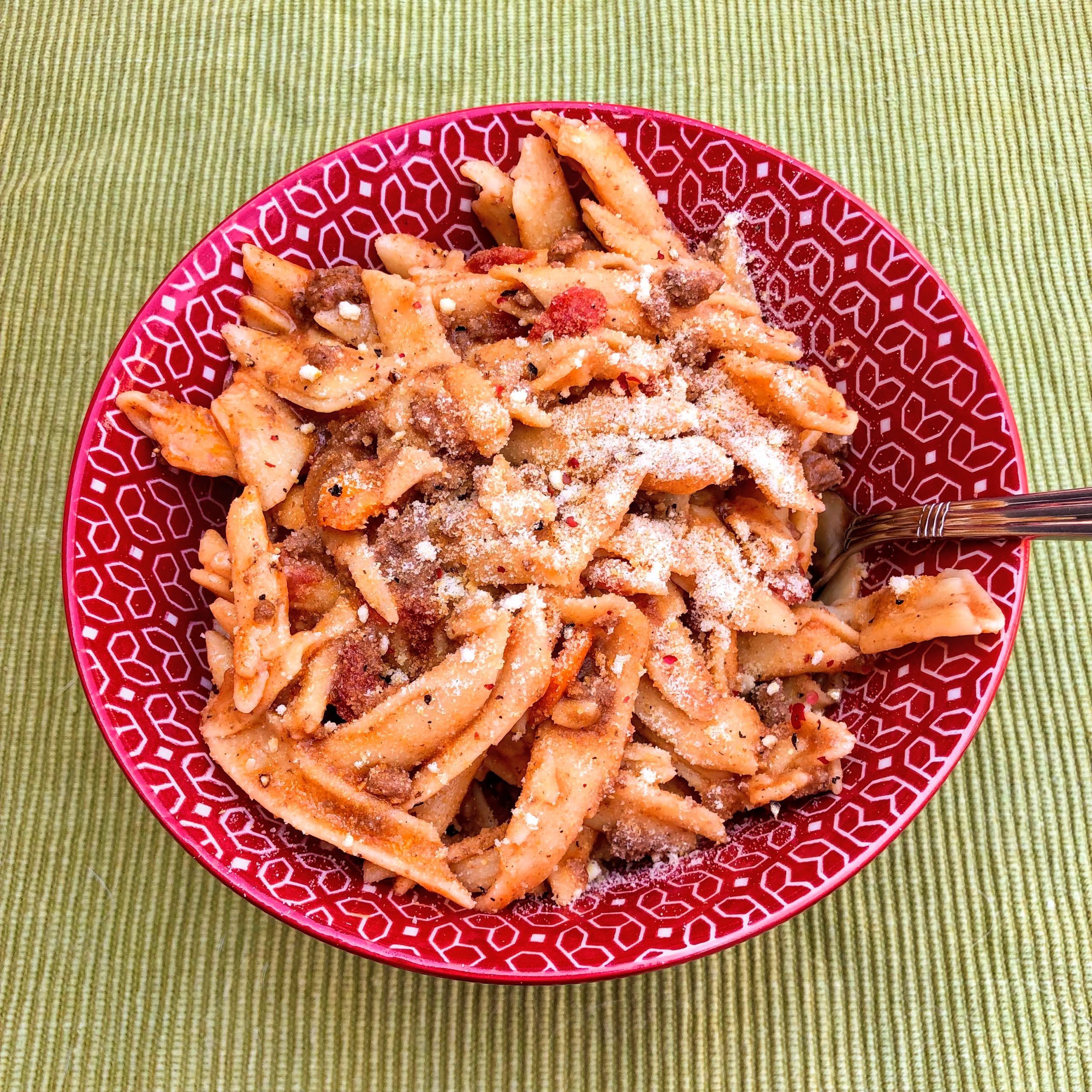 Leftover The ONE Beef and Veggies Sauce with Penne Pasta in a red bowl on a green placemat