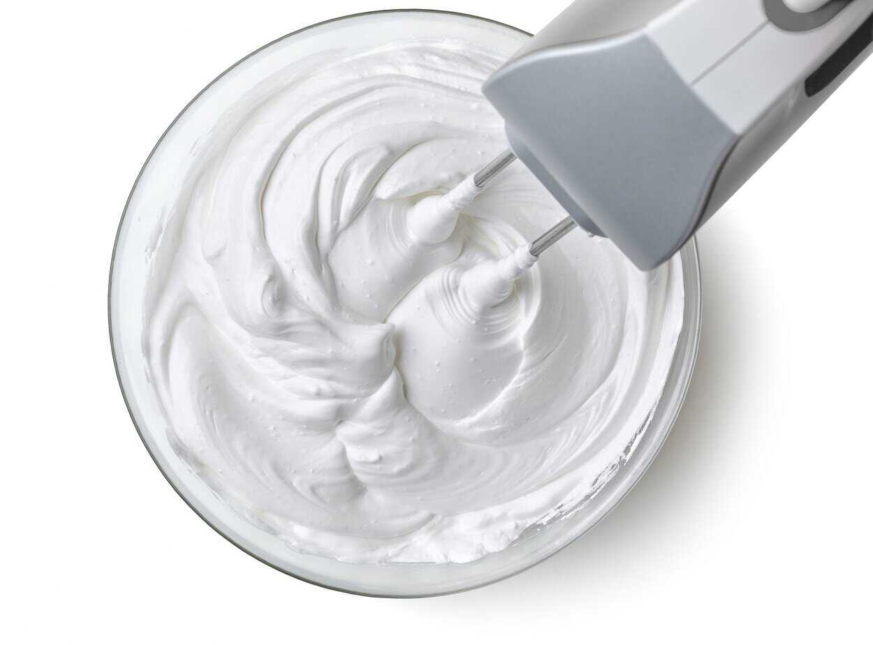 bowl of whipped egg whites Dairy-free whipped coconut topping in glass bowl being whipped with electric mixer showing soft peaks