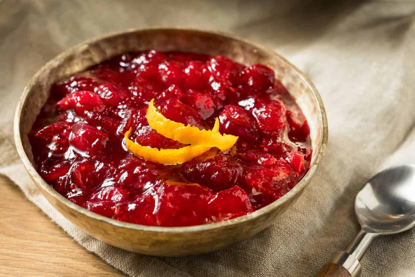 Sweet Homemade Cranberry Sauce Homemade cranberry orange sauce in wooden bowl garnished with orange zest