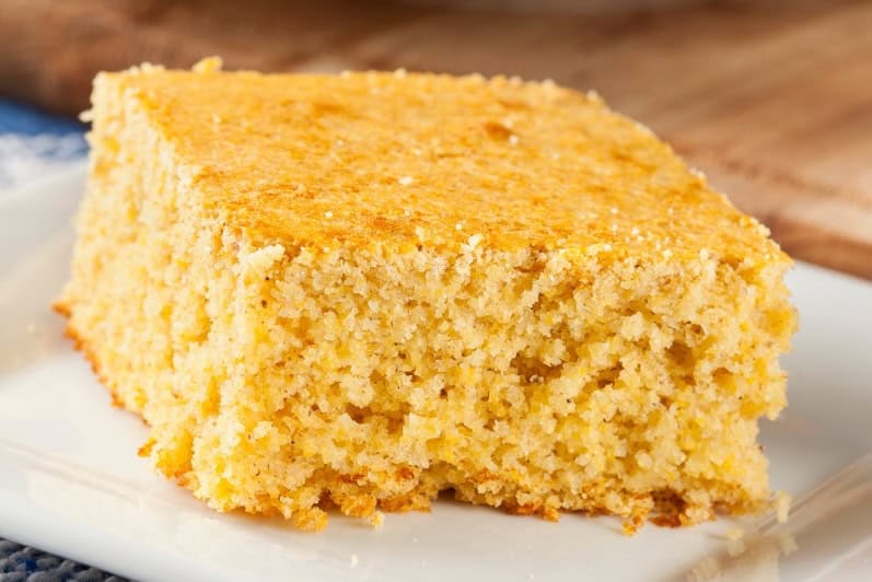 Landscape Images - Sliced-cornbread A close-up of a square slice of golden gluten-free cornbread on a white plate