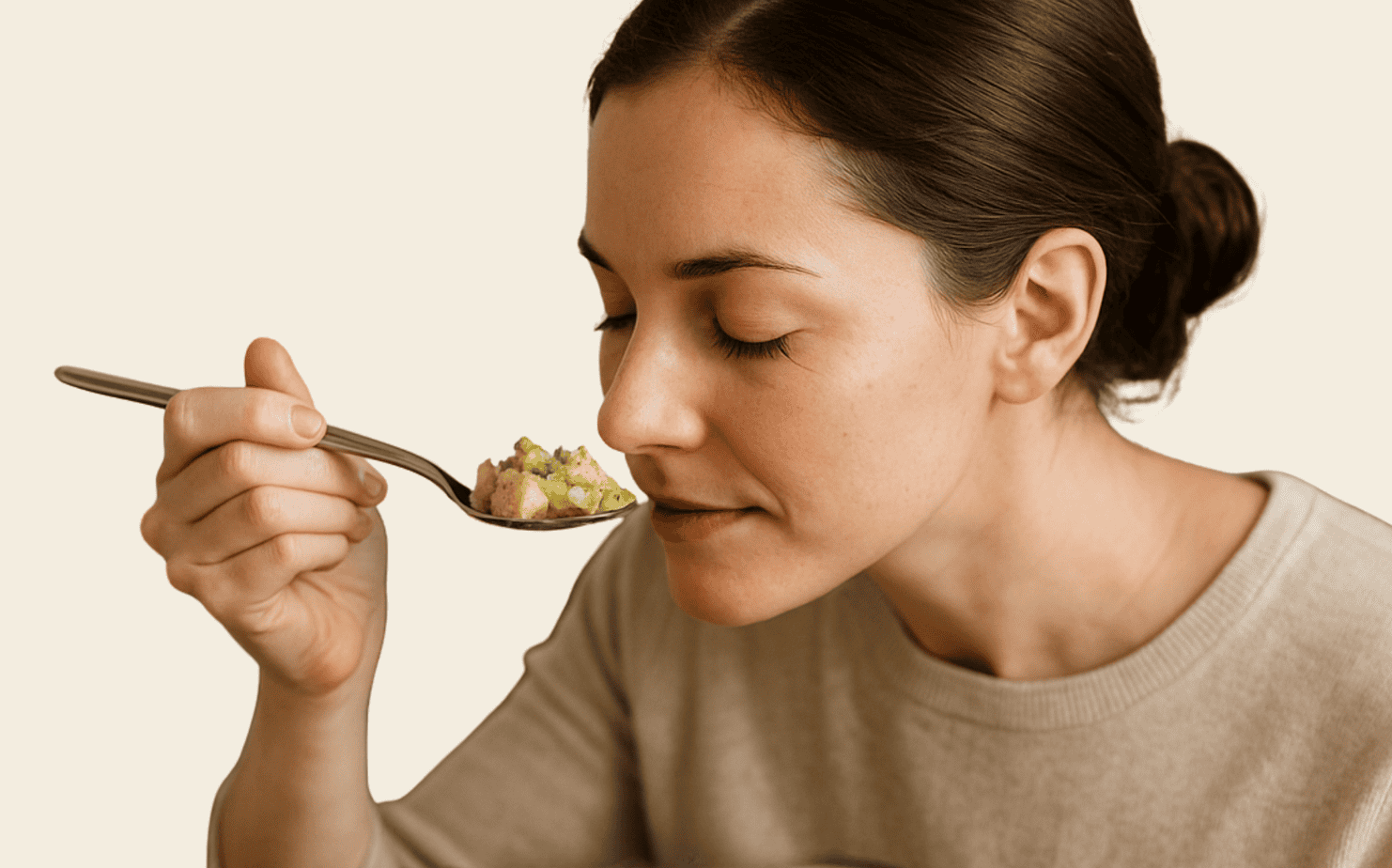 stuffing-sage-smell-test A woman standing and holding a spoonful of unbaked turkey stuffing—moist bread cubes with cooked celery, onions, and sage up toward her nose to test the aroma for sage