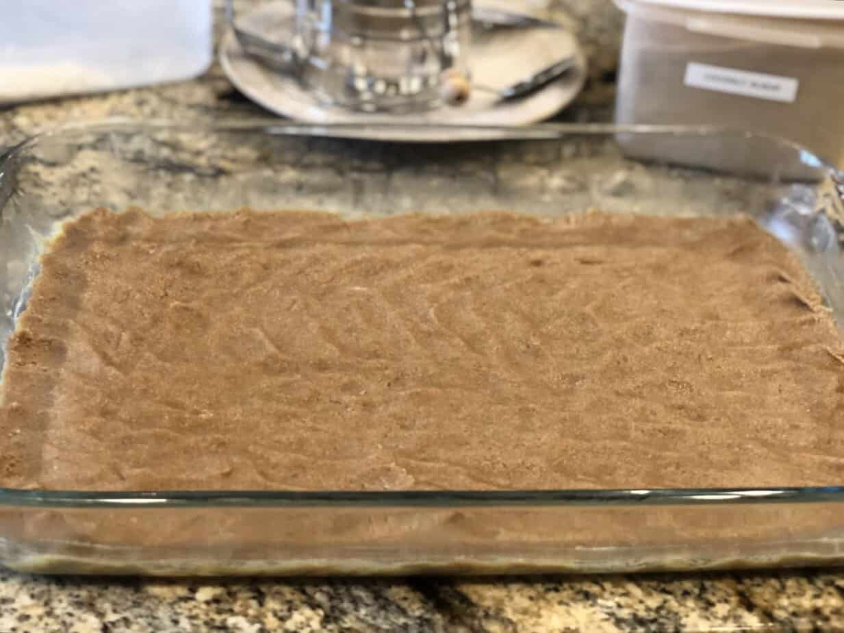 gluten-free-coconut-hazelnut-bars-unbaked-almond-flour-crust Unbaked almond flour crust pressed into a 13x9 glass baking dish for gluten-free coconut hazelnut bars