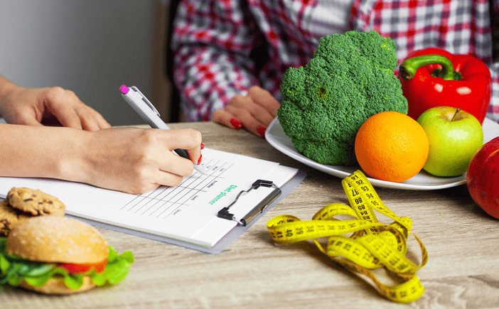 Nutrition consultation with a health professional reviewing a food plan alongside fresh produce
