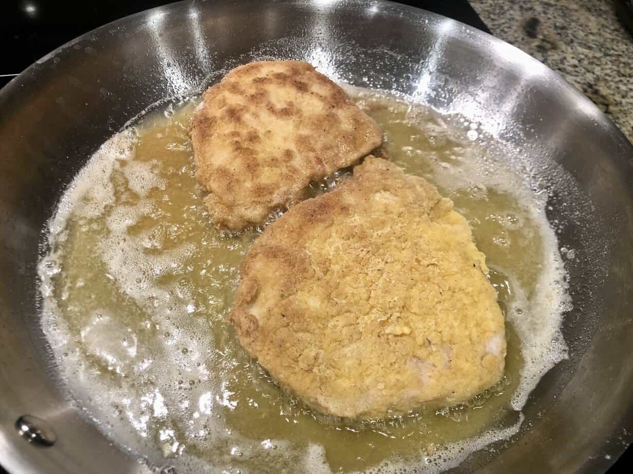 Frying Chicken-Fried Steak in a Stainless Skillet Two pieces of gluten-free chicken-fried steak frying in oil in a stainless steel skillet