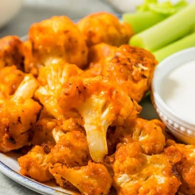 Plate of roasted buffalo cauliflower wings with celery sticks and ranch-style dipping sauce