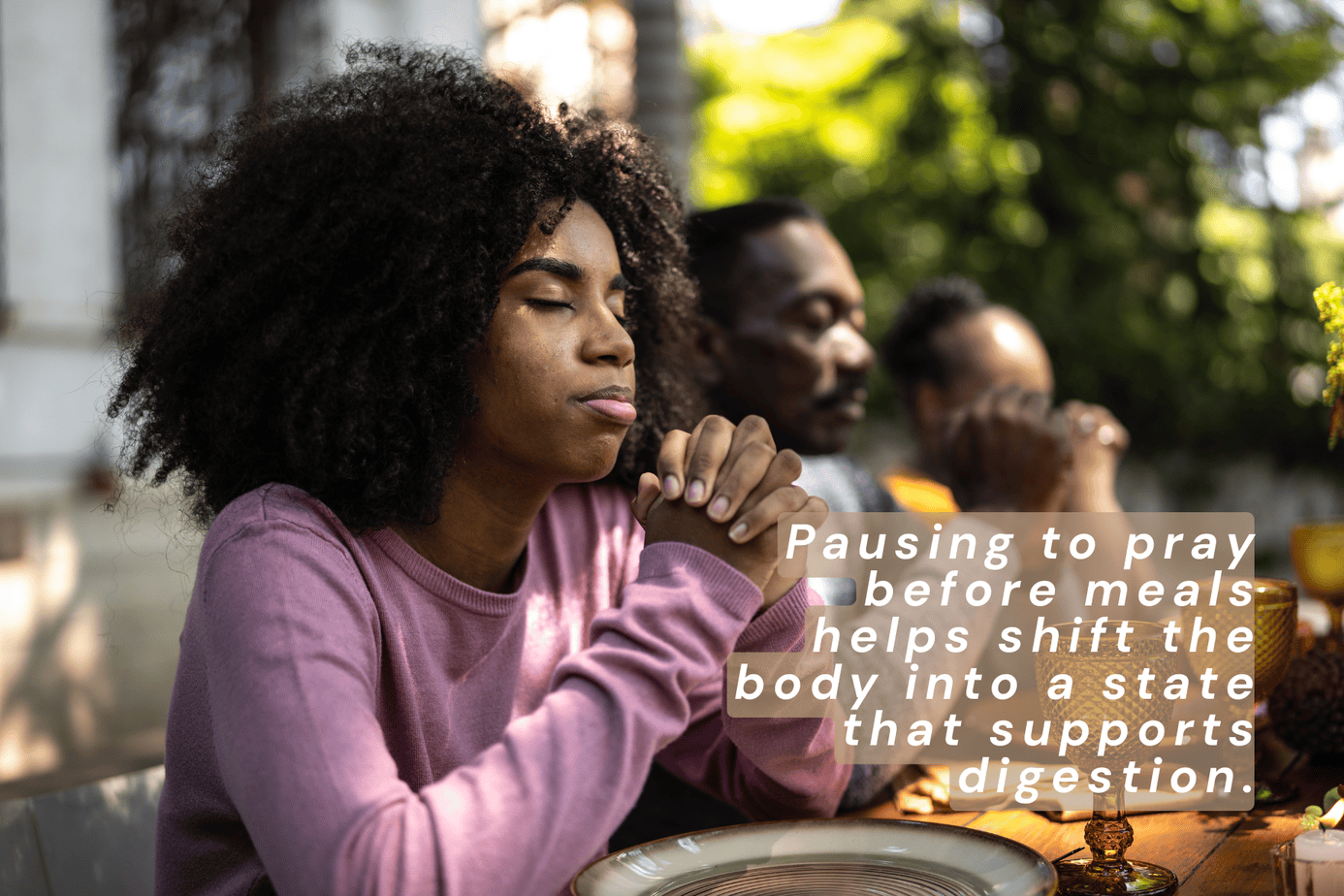 Three people pausing to pray before a meal outdoors, illustrating how gratitude before eating can help shift the nervous system into a state that supports digestion and gut health.