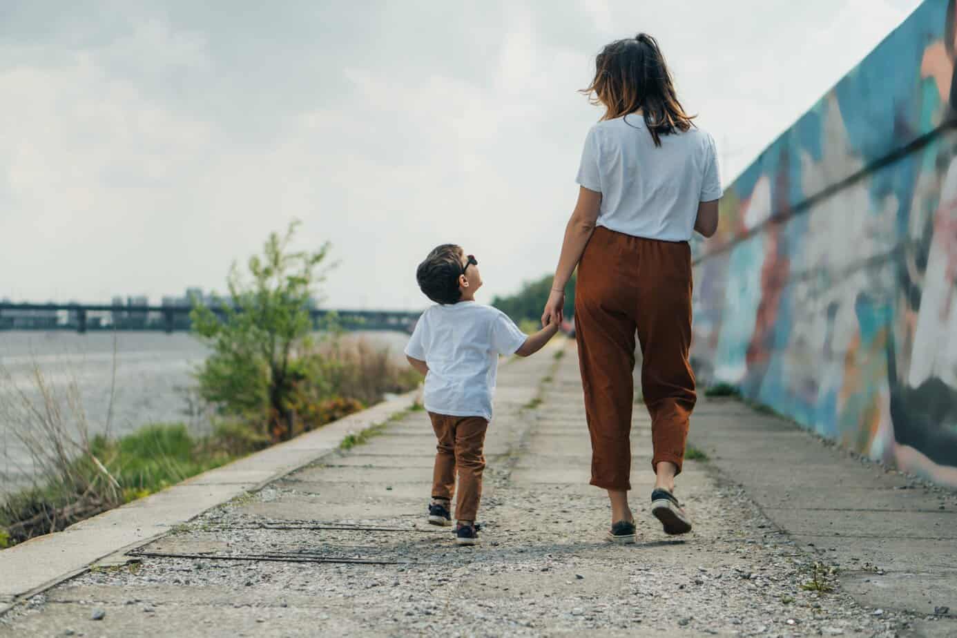 Mother and child walking forward together holding hands, symbolizing generational influence and the power to change what is passed on