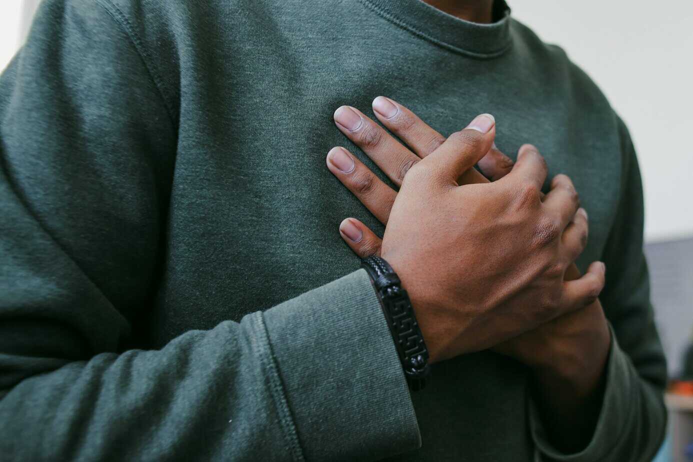 Person holding their chest with both hands, reflecting the connection between emotions, belief, and physical health
