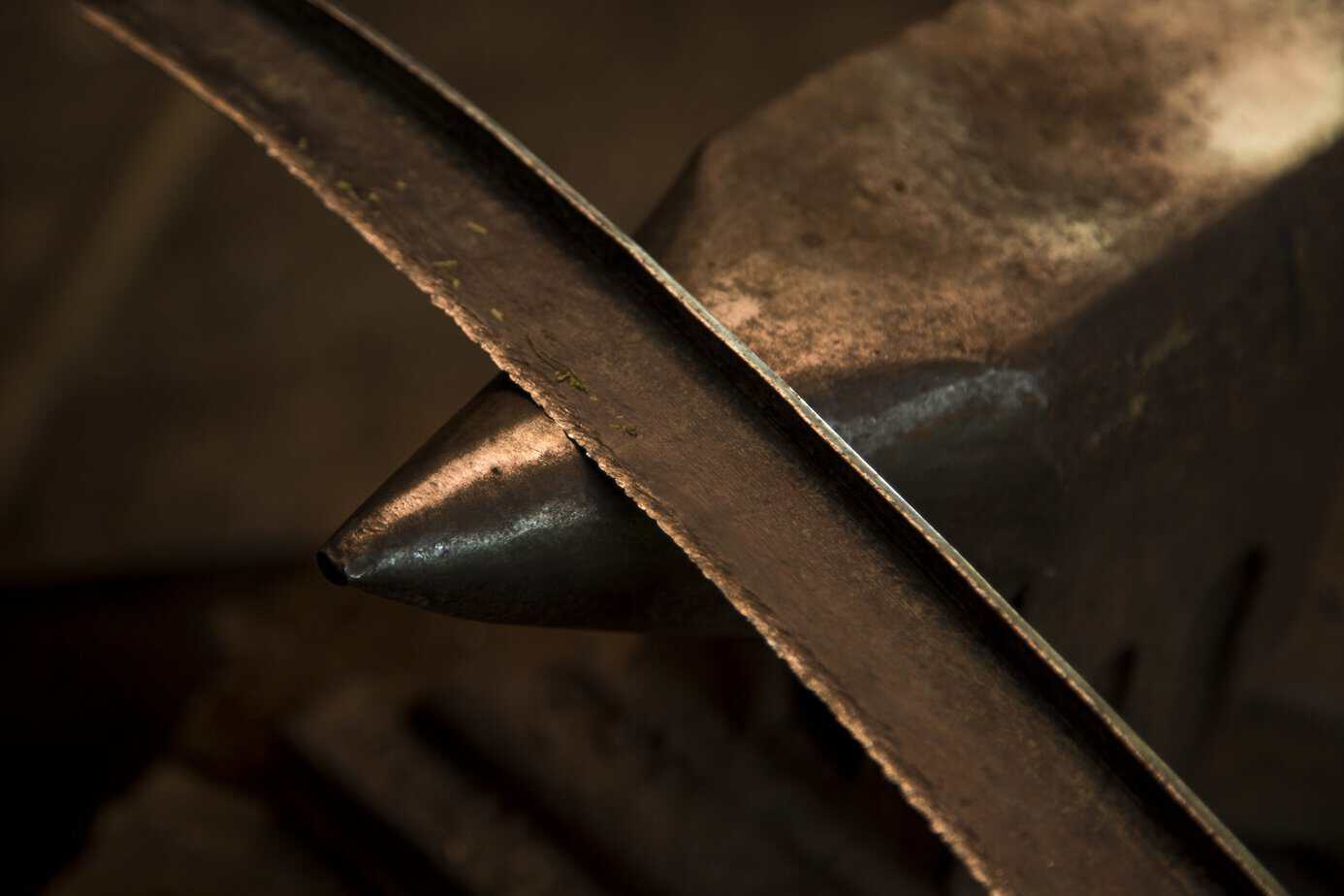 Blacksmith Hands sharpening metal on a workbench, illustrating the friction of change and ‘iron sharpens iron