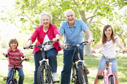 Senior couple with grandchildren on bikes Smiling grandparents riding bikes in a park with their two grandchildren, enjoying active, healthy time together as a family