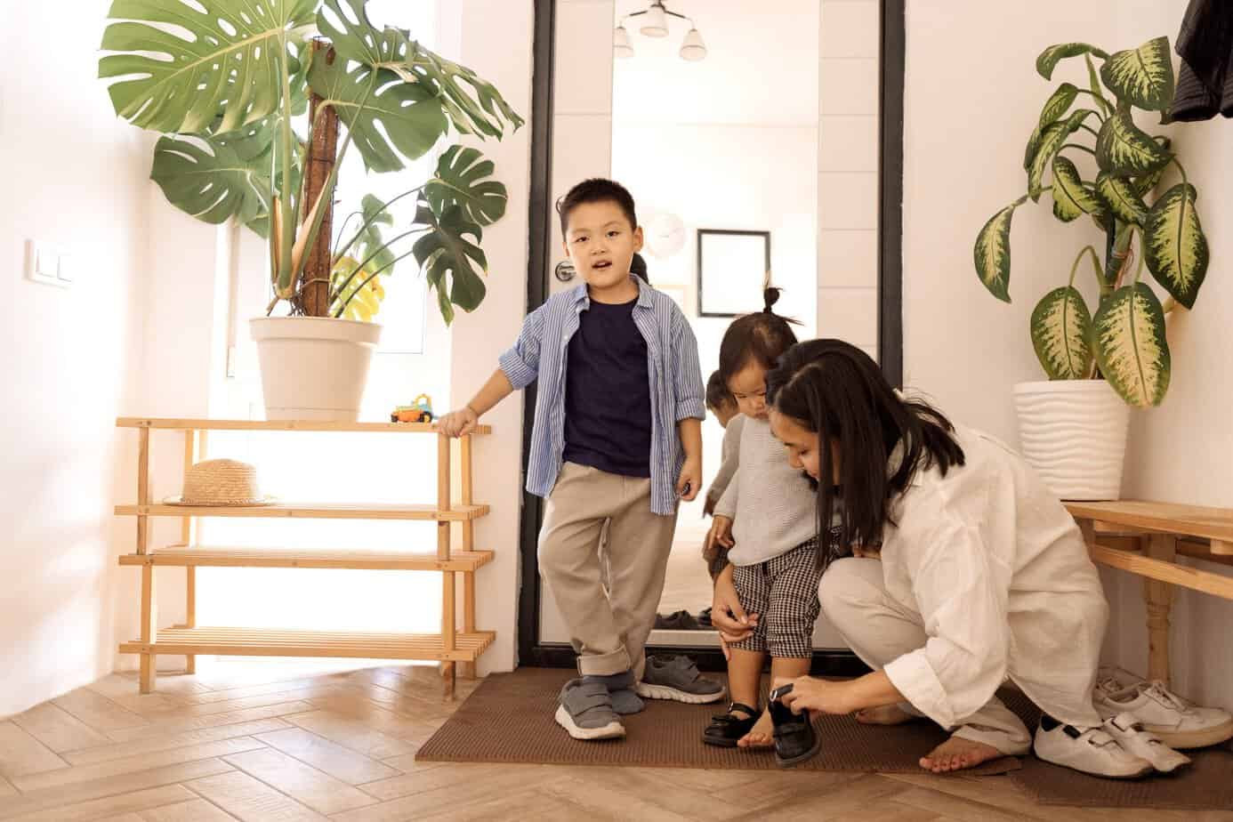 Children standing with a parent in the entryway, learning to take your shoes off at the door before going into the house