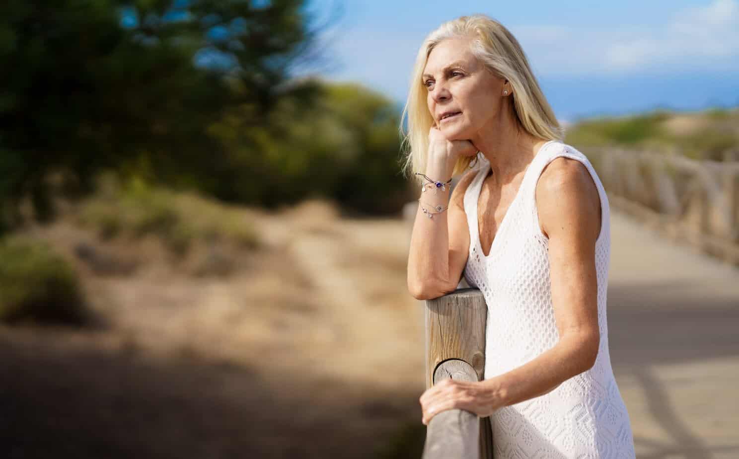 Woman standing thoughtfully on a nature trail, illustrating the connection between mindset and health