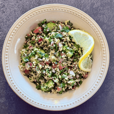 Gluten-Free Tabbouleh with millet, parsley, mint, cucumber, tomato, and lemon in a cream-colored bowl