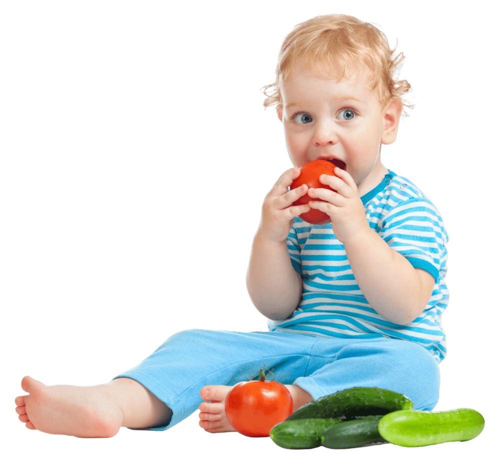 A happy baby sitting on the floor eating tomatoes and cucumbers