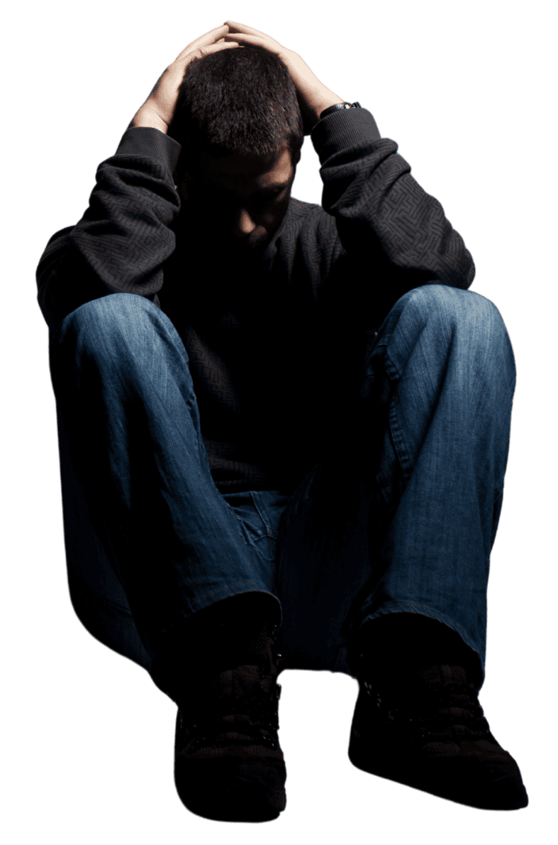 A man in dark clothes cowering in fear seated on the floor