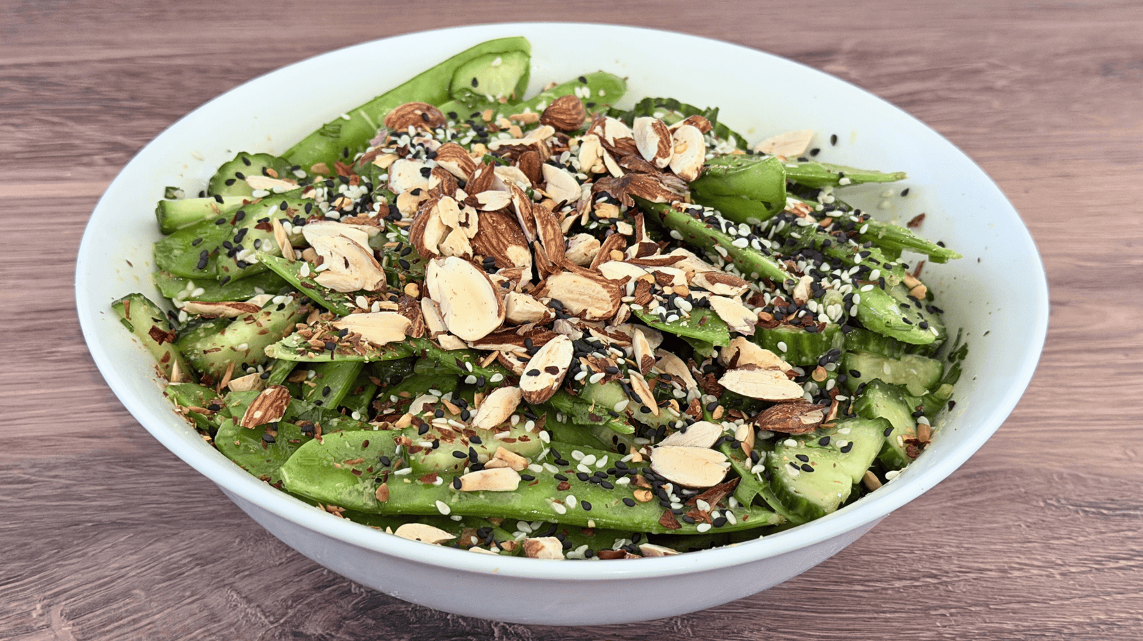 Sesame Snow Pea Salad Hero Image Sesame Snow Pea Salad with cucumber, toasted almonds, black and white sesame seeds, cilantro, and a ginger-sesame dressing