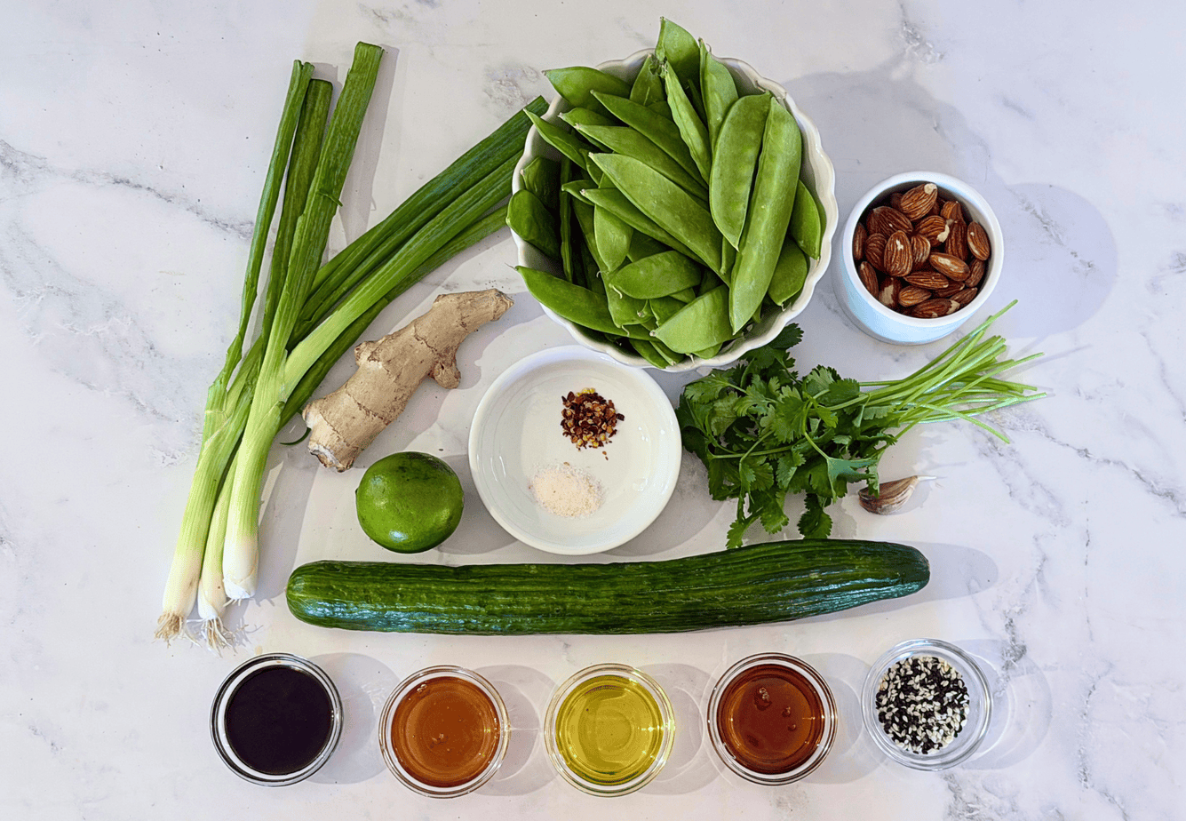 Sesame Snow Pea Salad Ingredients Ingredients for Sesame Snow Pea Salad, including snow peas, cucumber, scallions, cilantro, almonds, ginger, lime, and sesame seeds
