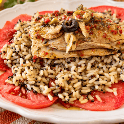 Mediterranean mackerel plate with olives and herbs over warm brown rice, quinoa, and fresh tomato slices